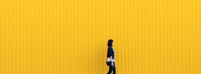 person-walking-in-front-of-yellow-wall
