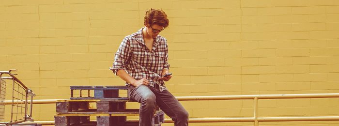 person-sitting-on-pallets-looking-at-phone