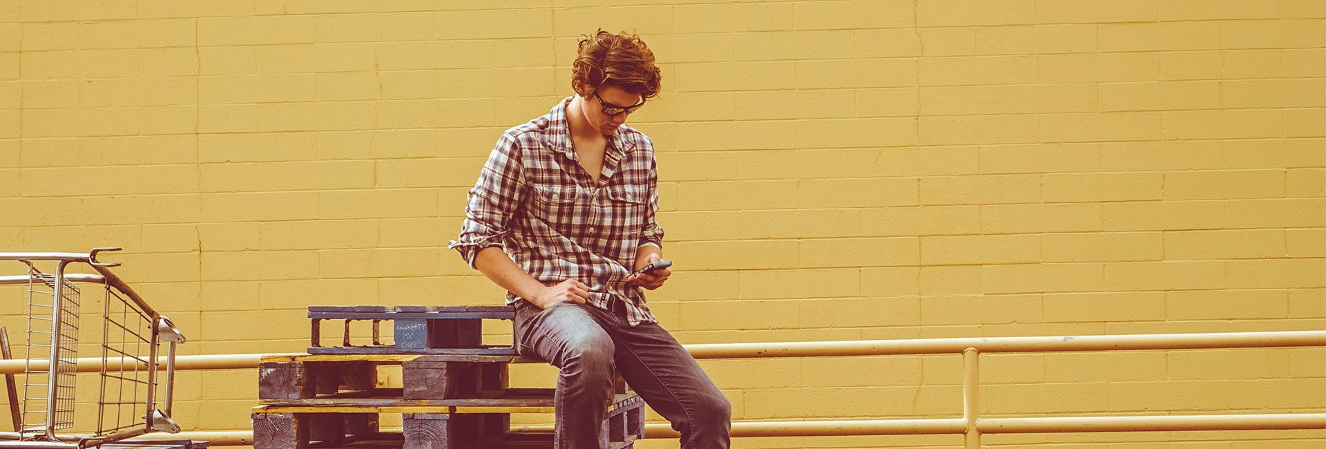 person-sitting-on-pallets-looking-at-phone