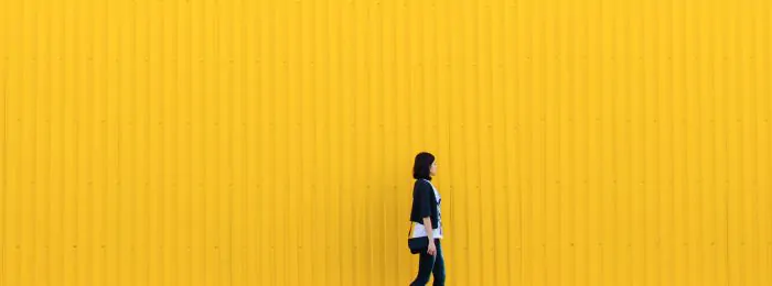 person-walking-in-front-of-yellow-wall