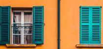 Mustard yellow building with windows, teal shutters