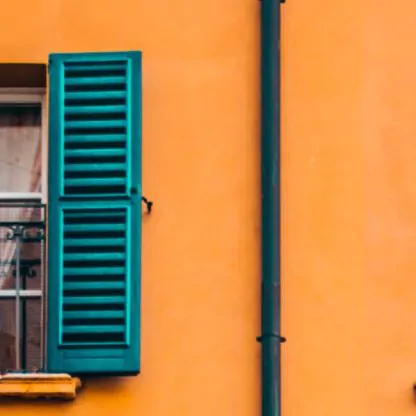 Mustard yellow building with windows, teal shutters
