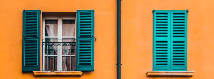 Mustard yellow building with windows, teal shutters