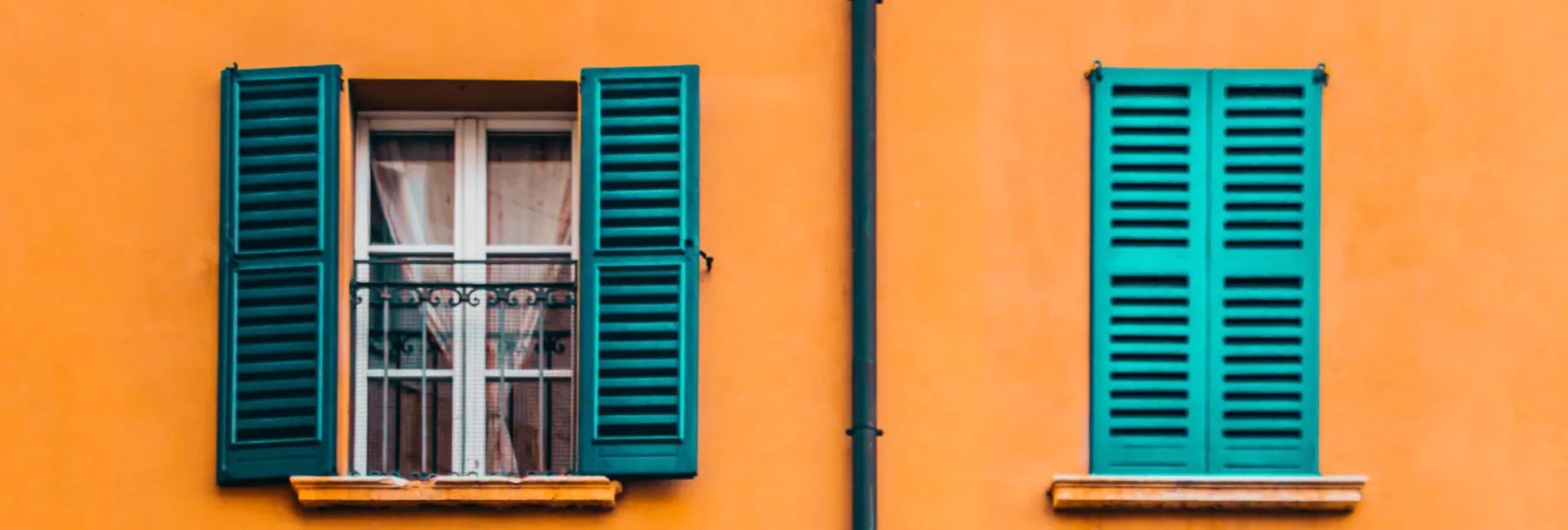 Mustard yellow building with windows, teal shutters