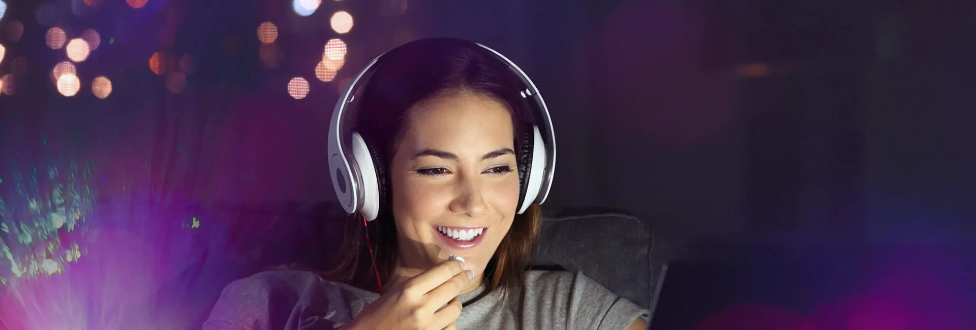 Single woman watching online tv in the night sitting on a couch in the living room at home